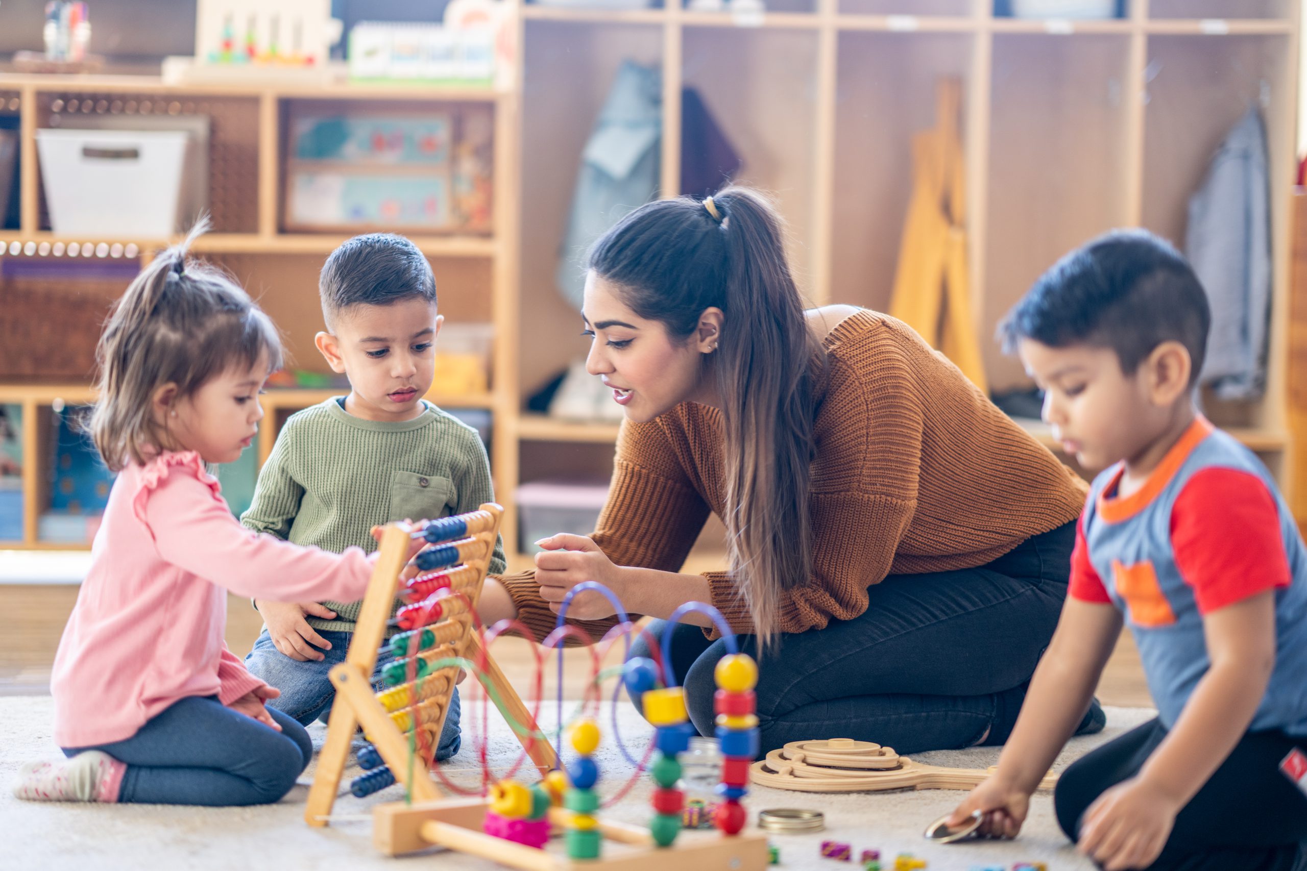 Therapist sitting with the children sitting in the floor as they play with various toys and engage in different activities in the speech and language therapy clinic.