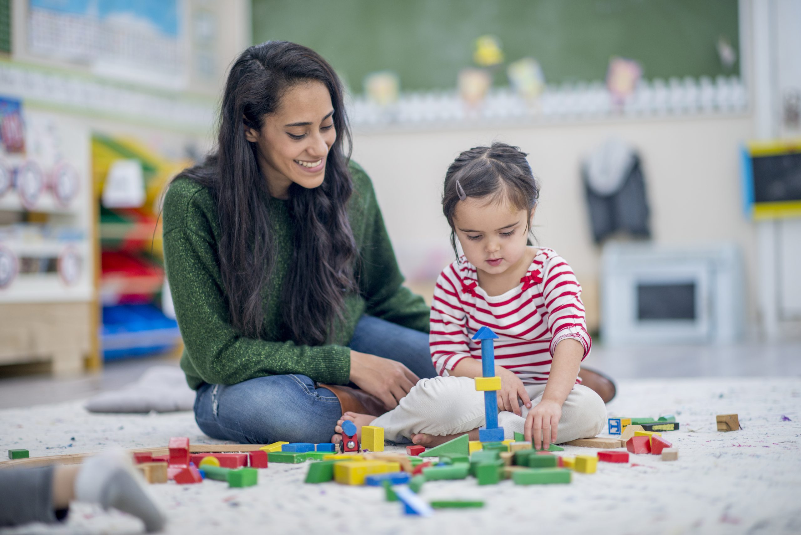 Therapist helping a little girl playing with blocks in the best speech and language therapy clinic.